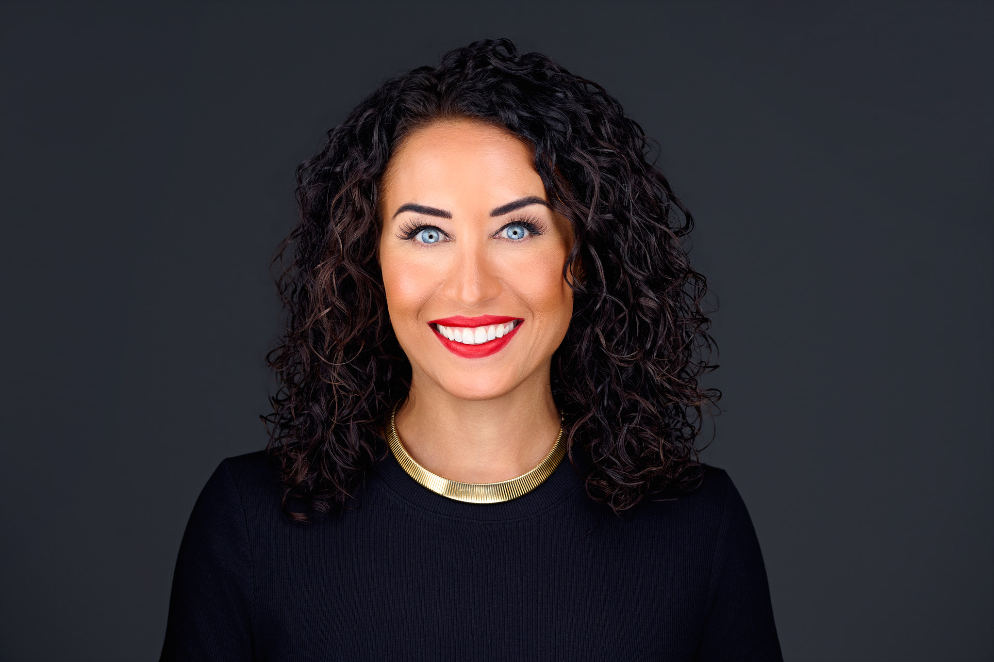 Dr. Tara Chalakani smiling in a black top and gold collar necklace